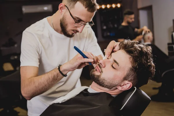 理容室で流行の散髪をしている若い男 理髪師は髪とひげのトリムを行います コンセプト Barbershop — ストック写真