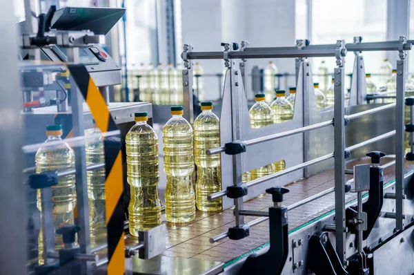 Bottling line of sunflower oil in bottles at plant, high technology concept, industrial background