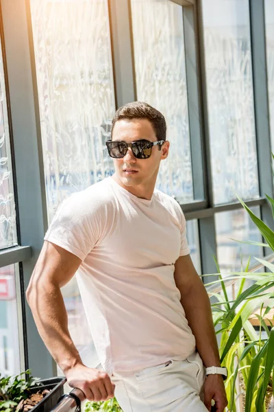 Pencereye poz veren gülümseyen genç adam portresi.