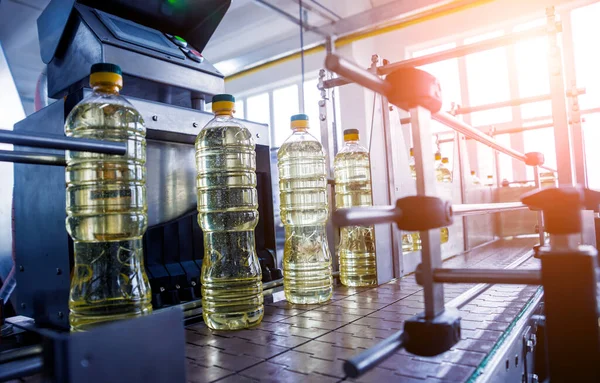 Bottling line of sunflower oil in bottles at plant, high technology concept, industrial background