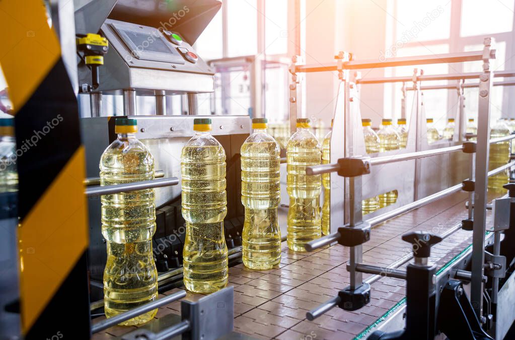 Bottling line of sunflower oil in bottles at plant, high technology concept, industrial background 