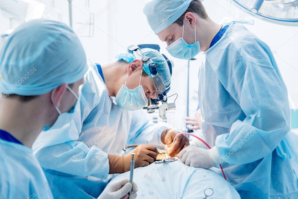Spinal surgery. Group of surgeons in operating room with surgery equipment. Laminectomy. Modern medical background