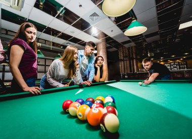 Bilardo oynayan bir grup neşeli genç arkadaş. İşten sonra eğlenceli zamanlar.