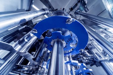 Otomatik doldurma makinesi plastik şişelere su dolduruyor, endüstriyel arka plan