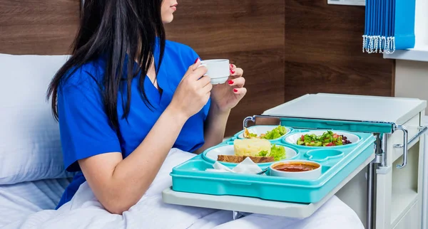 young woman eating in hospital, tray with breakfast for patient