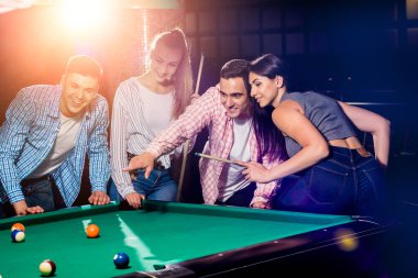 Bilardo oynayan bir grup neşeli genç arkadaş. İşten sonra eğlenceli zamanlar.
