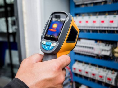 Fünye kutusundaki sıcaklığı kontrol etmek için kızılötesi termal görüntüleme kamerası kullanan teknisyenleri kapat
