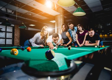 Bilardo oynayan bir grup neşeli genç arkadaş. İşten sonra eğlenceli zamanlar.