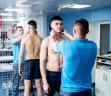 Rehabilitasyon merkezinde genç bir erkek hastayla çalışan bir fizyoterapist. Tedavi