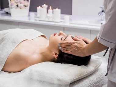Güzeller güzeli genç bir kadın spa salonunda kafa masajı yapıyor. Kozmetoloji kavramı