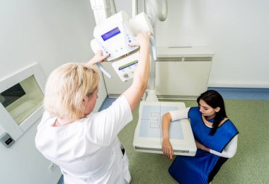Radyolog ve hasta röntgen odasında. İnsan elinin röntgeni. Klasik tavana monte edilmiş x-ray sistemi