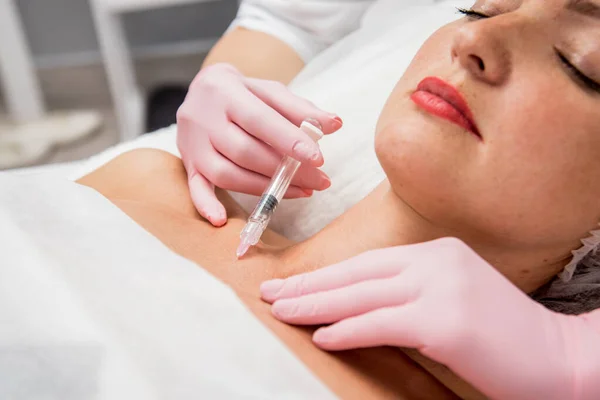 De arts cosmetoloog maakt de neklijn injecties procedure. Jonge vrouw in een schoonheidssalon. — Stockfoto