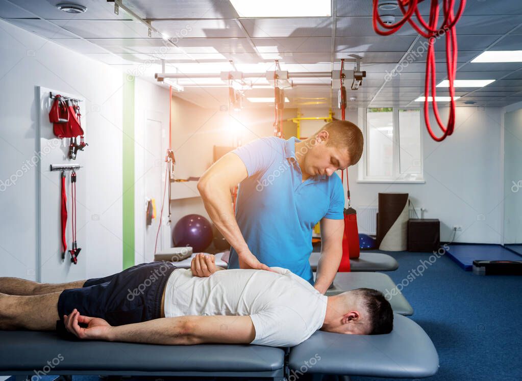 Rehabilitation therapy. Physiotherapist working with young male patient in the rehabilitation center. Treatment pain in spine