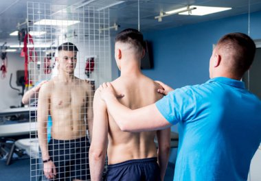 Rehabilitasyon merkezinde genç bir erkek hastayla çalışan bir fizyoterapist. Tedavi