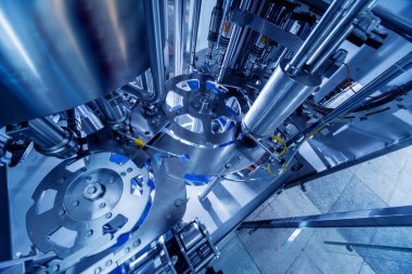 Otomatik doldurma makinesi plastik şişelere su dolduruyor, endüstriyel arka plan