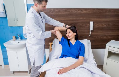 Travmatolog modern hastanedeki hastaların ellerini inceliyor.