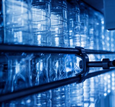 Otomatik doldurma makinesi plastik şişelere su dolduruyor, endüstriyel arka plan