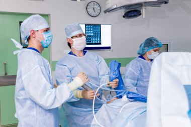 Artroskop ameliyatı. Modern artroskopik aletlerle ameliyathanede takım çalışması yapan ortopedik cerrahlar. Diz ameliyatı. Hastane geçmişi