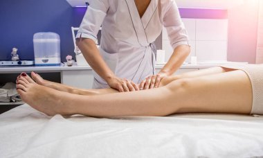Güzeller güzeli genç bir kadın spa salonunda bacak masajı yapıyor. Kozmetoloji kavramı