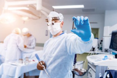 Omurga ameliyatı. Cerrahlar ameliyathanede ameliyat malzemeleriyle poliaxial vida olduğunu gösteriyor. Laminektomi. Omurga saplantı sistemleri. Tıbbi geçmiş