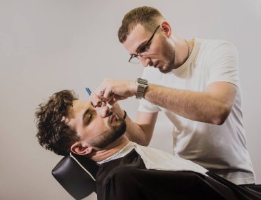 Berber dükkanında son moda saç kesimi olan genç bir adam. Berber saç ve sakal kesimi yapıyor. Berber dükkanı kavramı.