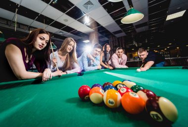 Bilardo oynayan bir grup neşeli genç arkadaş. İşten sonra eğlenceli zamanlar.