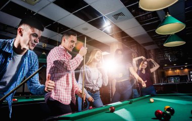 Bilardo oynayan bir grup neşeli genç arkadaş. İşten sonra eğlenceli zamanlar.