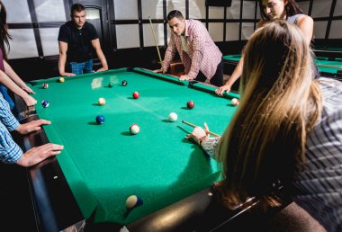 Bilardo oynayan bir grup neşeli genç arkadaş. İşten sonra eğlenceli zamanlar.