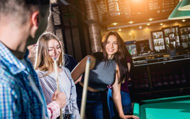 Bilardo oynayan bir grup neşeli genç arkadaş. İşten sonra eğlenceli zamanlar.