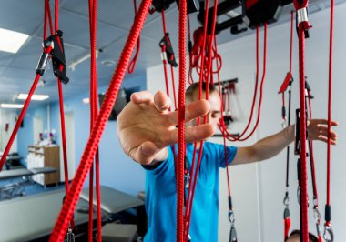 Uzaklaştırma eğitim terapisi. Genç adam süspansiyon temelli egzersiz sistemiyle fitness çekiş terapisi yapıyor.