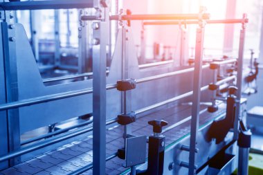 Otomatik doldurma makinesi plastik şişelere su dolduruyor, endüstriyel arka plan