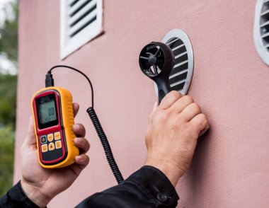 Teknisyen, hava akışı ölçümlerini elle ölçen anemometre kullanıyor