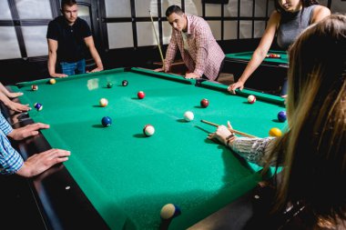 Bilardo oynayan bir grup neşeli genç arkadaş. İşten sonra eğlenceli zamanlar.