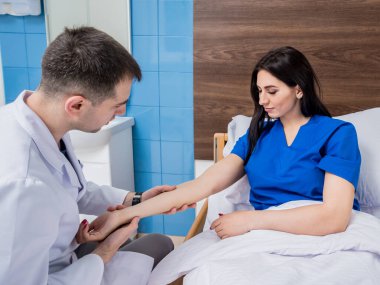 Travmatolog modern hastanedeki hastaların ellerini inceliyor.