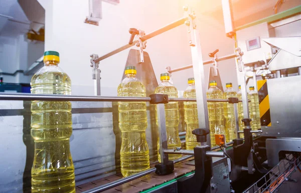 Bottling line of sunflower oil in bottles at plant, high technology concept, industrial background