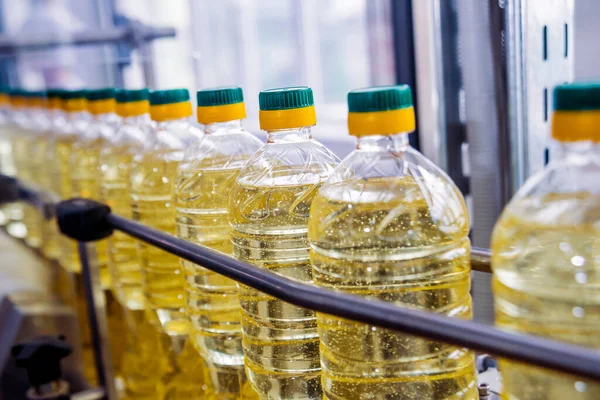 Bottling line of sunflower oil in bottles at plant, high technology concept, industrial background