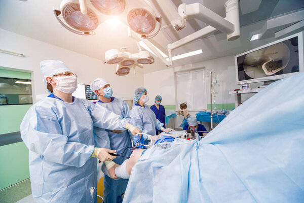 Операция артроскопом. Ортопедические хирурги в совместной работе в операционной с современными артроскопическими инструментами. Операция на коленях. Больничное прошлое