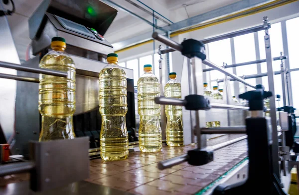 Bottling line of sunflower oil in bottles at plant, high technology concept, industrial background