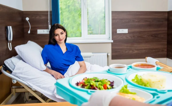 young woman eating in hospital, tray with breakfast for patient