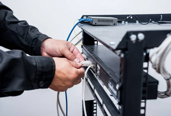 close up of technician connecting network cables to switches