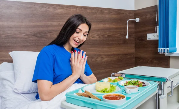 young woman eating in hospital, tray with breakfast for patient