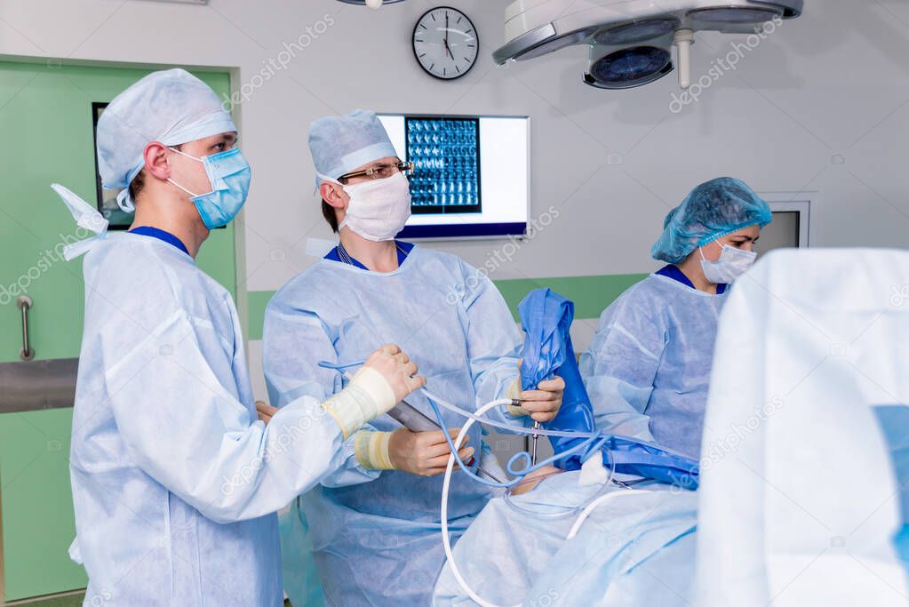 Arthroscope surgery. Orthopedic surgeons in teamwork in the operating room with modern arthroscopic tools. Knee surgery. Hospital background