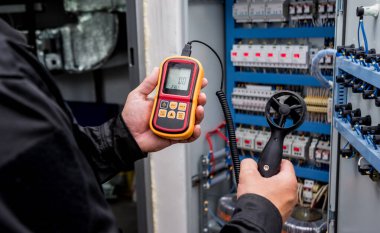 Teknisyen, hava akışı ölçümlerini elle ölçen anemometre kullanıyor