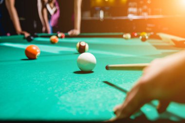 Genç adam bilardoda topa vurmaya çalışıyor. Arka plandaki arkadaşları..