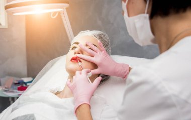 Doktor kozmetik uzmanı yüz enjeksiyonu prosedürünü uygular. Güzellik salonunda genç bir kadın. Kozmetoloji kavramı.