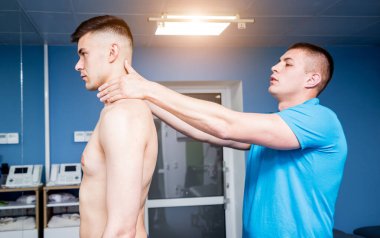 Rehabilitasyon merkezinde genç bir erkek hastayla çalışan bir fizyoterapist. Tedavi