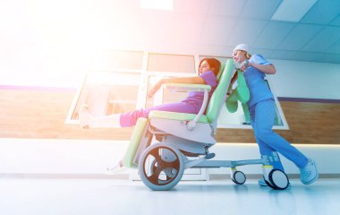 Hemşire hastanedeki hastayla seyyar tıbbi sandalyeyi hareket ettiriyor. Tıbbi ekipman. Kavram