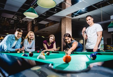 Bilardo oynayan bir grup neşeli genç arkadaş. İşten sonra eğlenceli zamanlar.