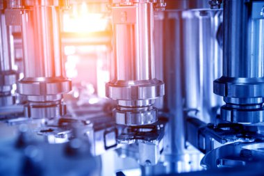 Otomatik doldurma makinesi plastik şişelere su dolduruyor, endüstriyel arka plan