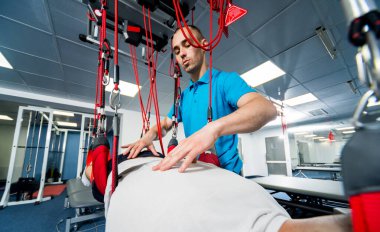 Uzaklaştırma eğitim terapisi. Genç adam süspansiyon temelli egzersiz sistemiyle fitness çekiş terapisi yapıyor.